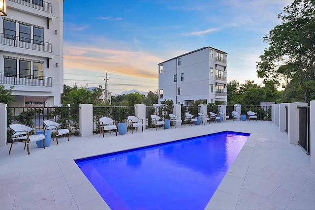 pool at dusk featuring a patio