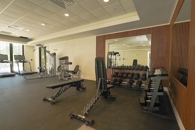 gym featuring baseboards, visible vents, a drop ceiling, and a tray ceiling