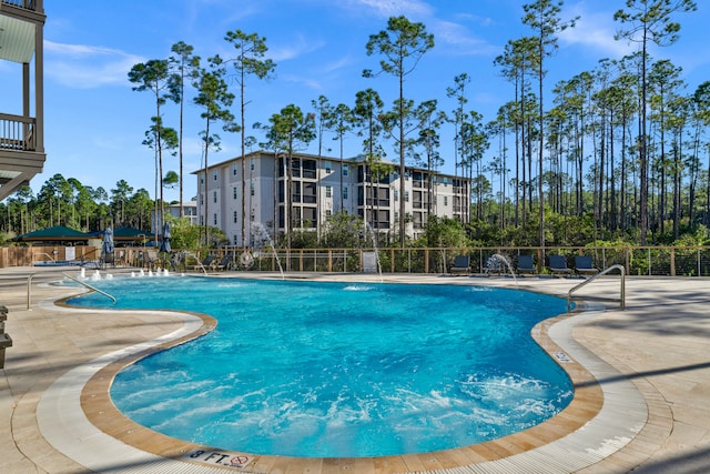 pool with a patio area and fence