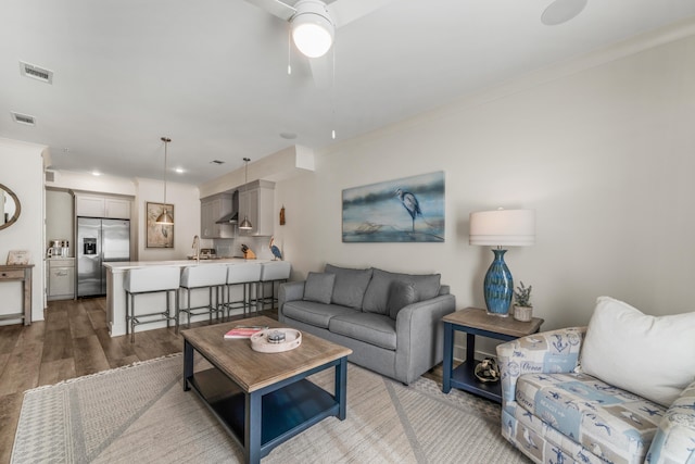 living area featuring crown molding, visible vents, ceiling fan, and wood finished floors