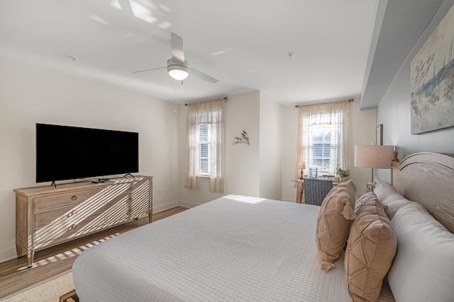 bedroom with ceiling fan, wood finished floors, and baseboards