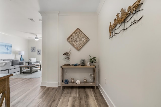 hall featuring baseboards, visible vents, and wood finished floors