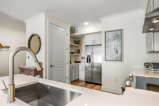 kitchen with light wood-type flooring, ornamental molding, extractor fan, sink, and stainless steel fridge with ice dispenser