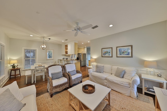 living room featuring ceiling fan with notable chandelier and hardwood / wood-style floors