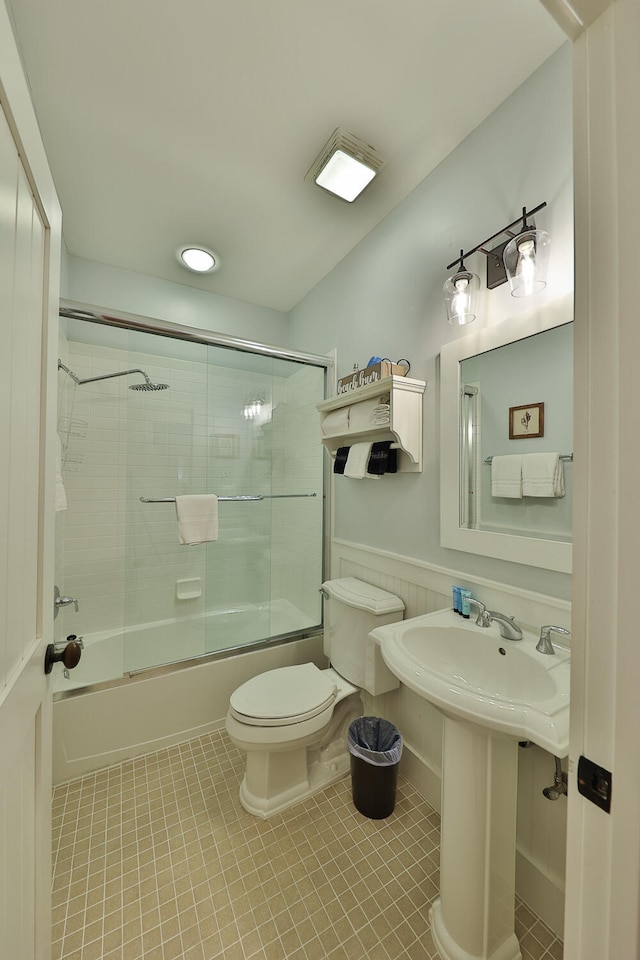 bathroom featuring shower / bath combination with glass door, toilet, and tile floors