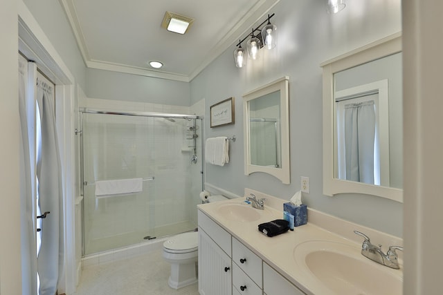 bathroom with crown molding, double sink, vanity with extensive cabinet space, a shower with door, and toilet