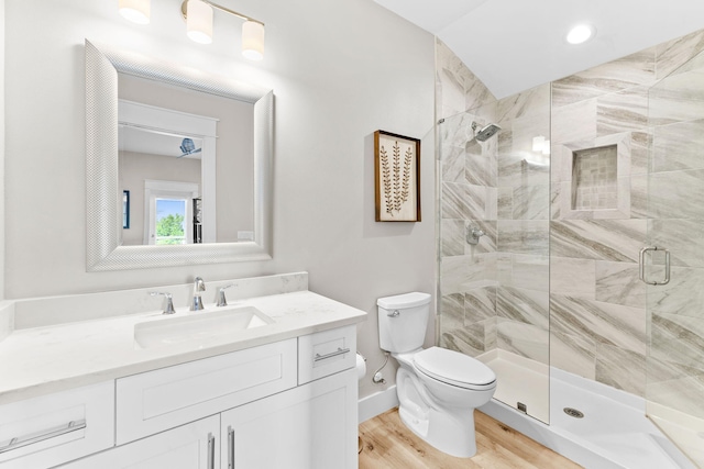 bathroom featuring a shower with shower door, hardwood / wood-style flooring, vanity, and toilet