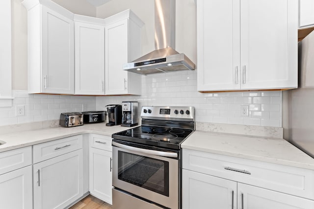 kitchen with white cabinetry, stainless steel electric stove, backsplash, and wall chimney exhaust hood