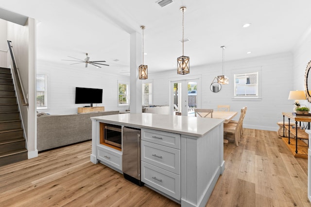 kitchen featuring hanging light fixtures, stainless steel microwave, and light hardwood / wood-style floors