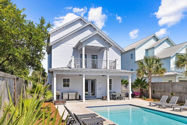 rear view of house featuring a patio, a balcony, and a fenced in pool