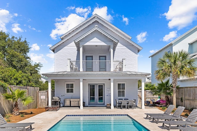 rear view of property with french doors, a patio area, a balcony, and a fenced in pool