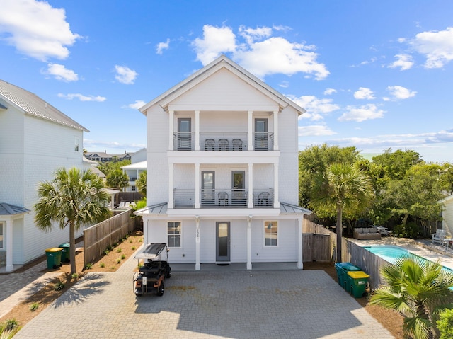 view of front of home featuring a fenced in pool, a balcony, and a patio