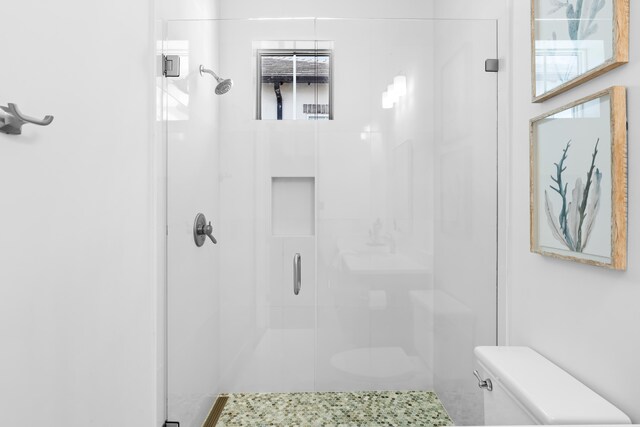 bathroom featuring a shower with shower door and toilet