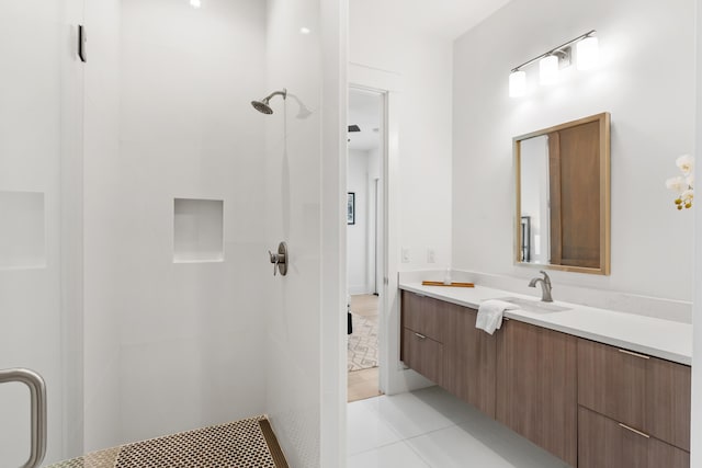 bathroom featuring a tile shower, vanity, and tile floors