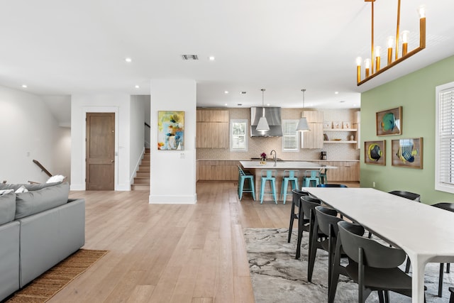 dining room with sink, light wood-type flooring, and a chandelier