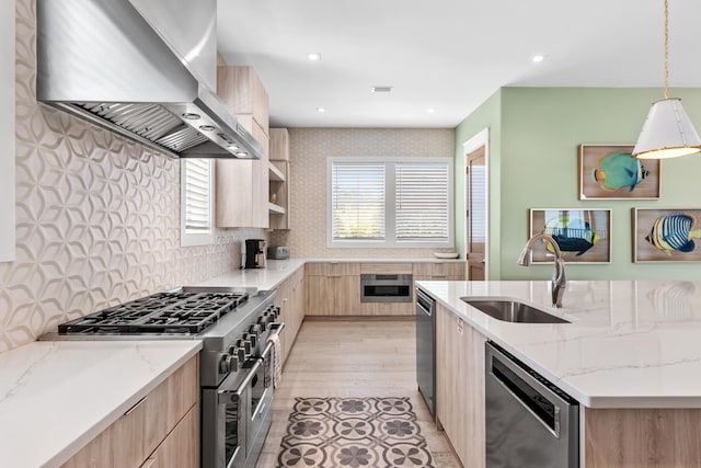 kitchen with wall chimney range hood, light hardwood / wood-style floors, stainless steel appliances, sink, and light brown cabinetry