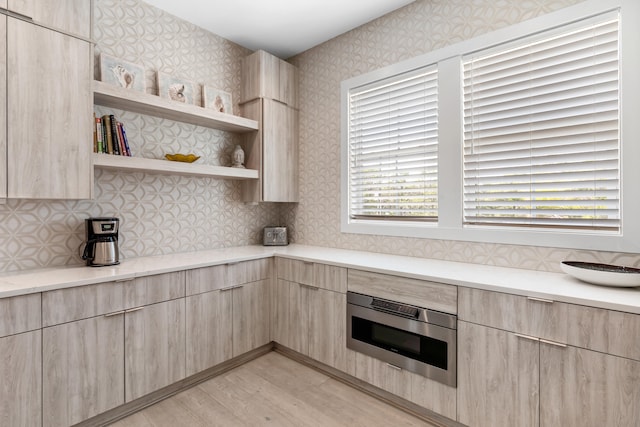 kitchen featuring light brown cabinets, oven, and light hardwood / wood-style floors