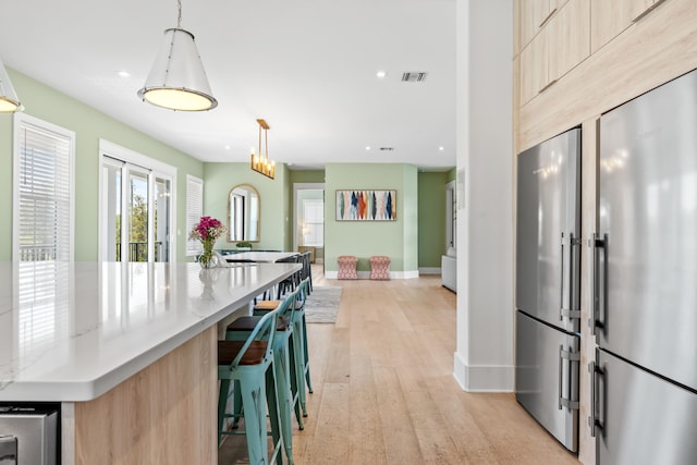 kitchen featuring a kitchen island, light brown cabinetry, light hardwood / wood-style flooring, and pendant lighting