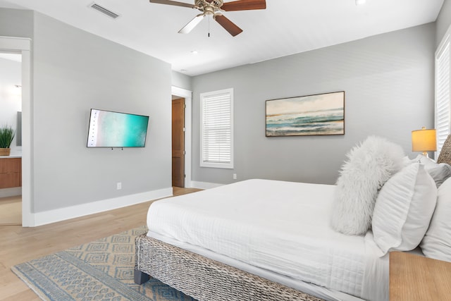 bedroom featuring ceiling fan, ensuite bathroom, and light hardwood / wood-style flooring