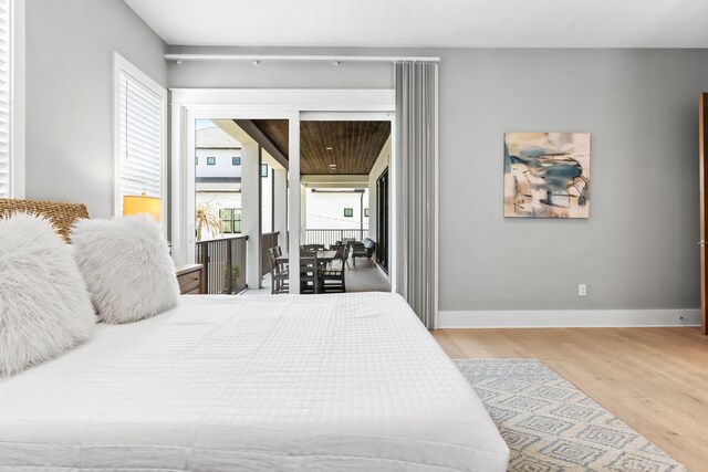 bedroom featuring multiple windows, light hardwood / wood-style flooring, and access to outside