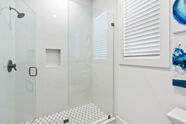 bathroom featuring a shower with door and toilet