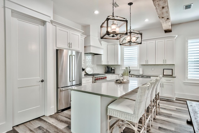 kitchen featuring a healthy amount of sunlight, light hardwood / wood-style floors, a center island, and premium appliances