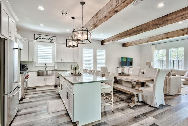 kitchen with white cabinets, light hardwood / wood-style floors, stainless steel appliances, beam ceiling, and sink