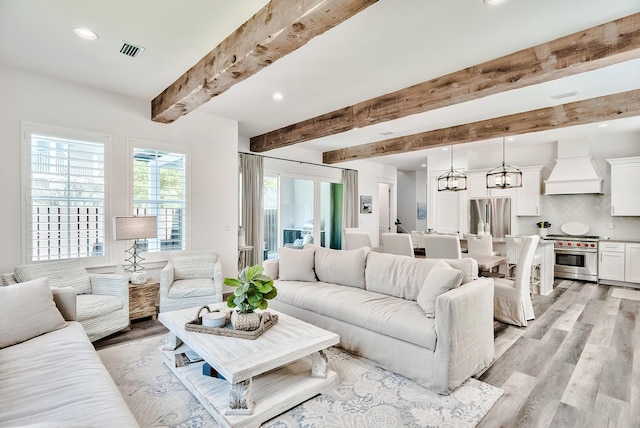 living room featuring beamed ceiling and light hardwood / wood-style flooring