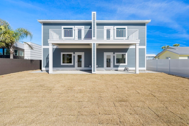 rear view of house featuring a patio area, french doors, a balcony, and a yard