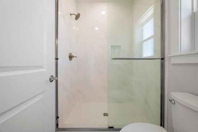 bathroom with a shower with shower door and toilet