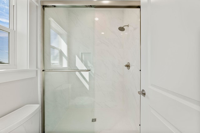 bathroom featuring plenty of natural light, an enclosed shower, and toilet