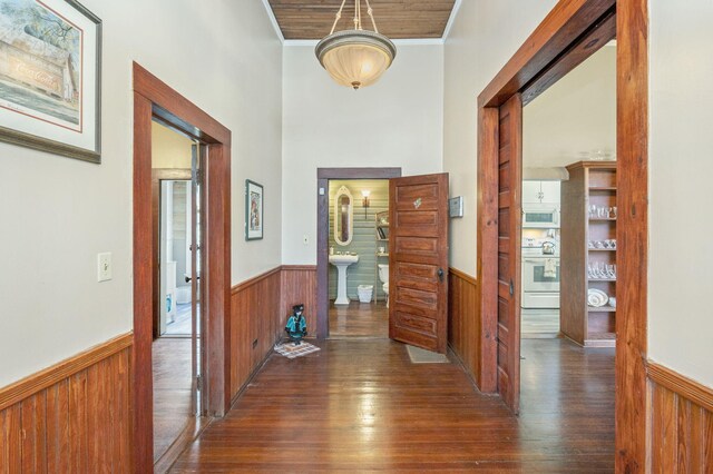 hall featuring a barn door, dark wood-type flooring, and ornamental molding