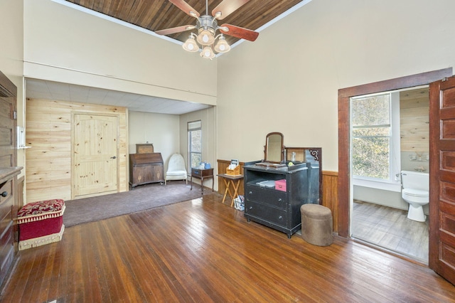 interior space with hardwood / wood-style floors, ceiling fan, and wooden walls