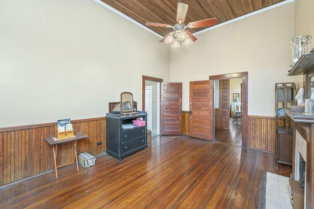 miscellaneous room featuring ornamental molding, ceiling fan, wooden ceiling, dark hardwood / wood-style floors, and a tiled fireplace