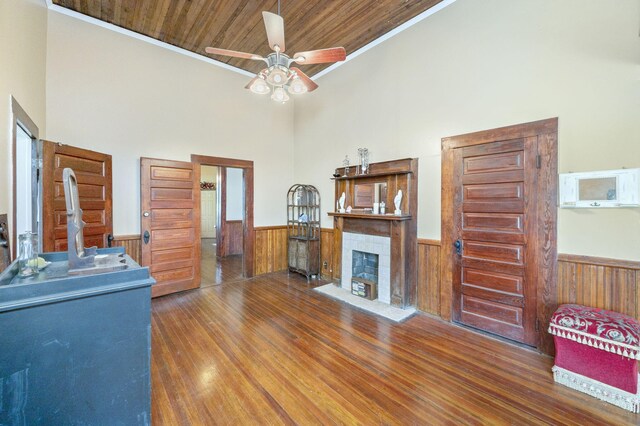 unfurnished living room featuring ceiling fan, dark hardwood / wood-style floors, wooden ceiling, and crown molding