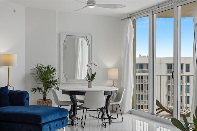 living area featuring ceiling fan and a wall of windows