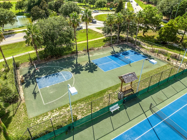 view of sport court featuring a lawn and a water view