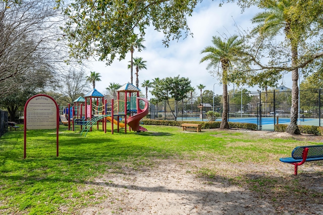 view of play area featuring tennis court and a lawn