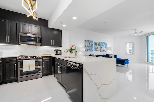 kitchen featuring kitchen peninsula, sink, decorative light fixtures, appliances with stainless steel finishes, and light stone counters