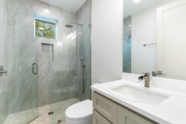 bathroom featuring an enclosed shower, vanity, and toilet