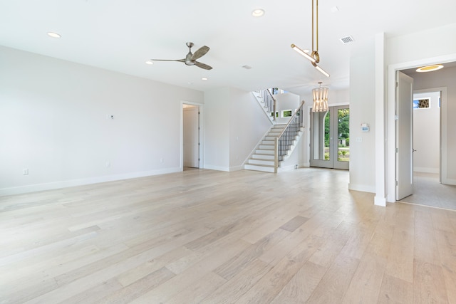 unfurnished living room with ceiling fan with notable chandelier, french doors, and light hardwood / wood-style flooring