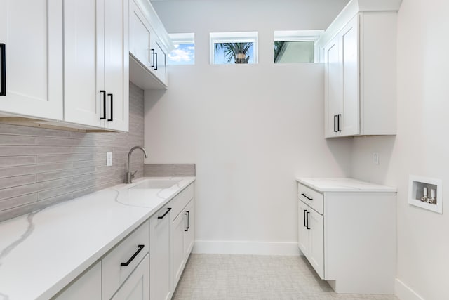 kitchen with sink, white cabinetry, and light stone counters