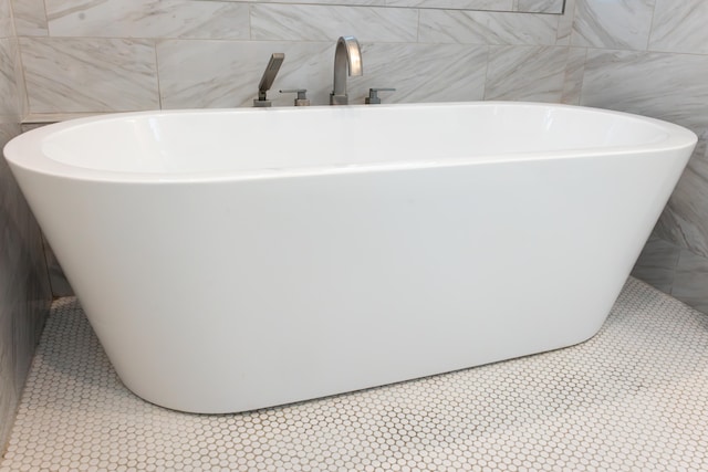 bathroom with tile patterned flooring and a tub to relax in