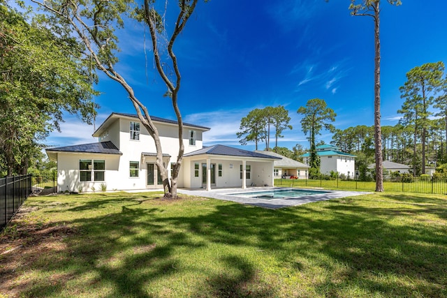 rear view of property featuring a yard, a fenced in pool, and a patio area