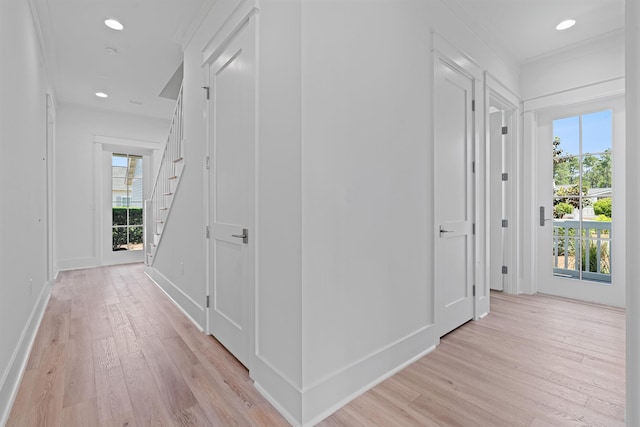 corridor featuring light hardwood / wood-style flooring, a healthy amount of sunlight, and ornamental molding