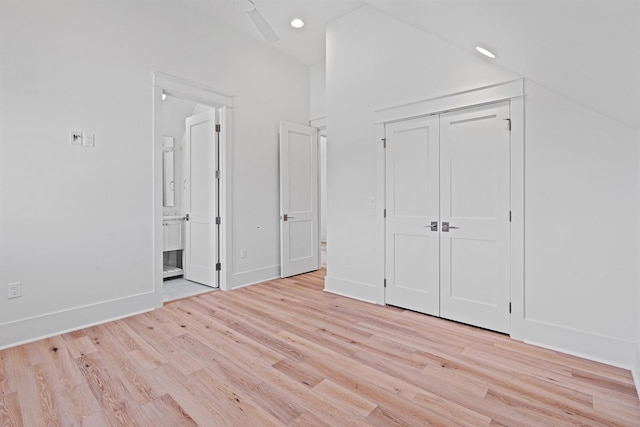 unfurnished bedroom with ceiling fan, a closet, light wood-type flooring, and vaulted ceiling