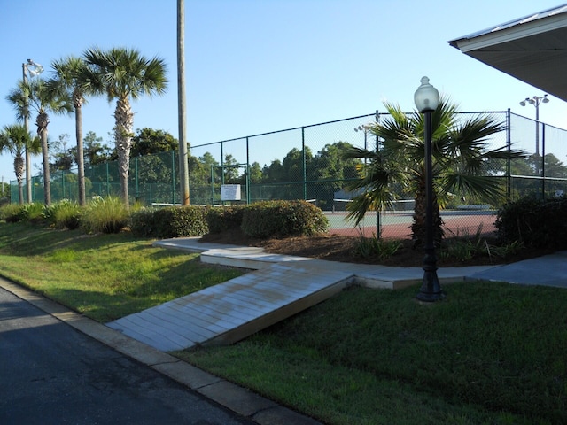 view of tennis court featuring a lawn