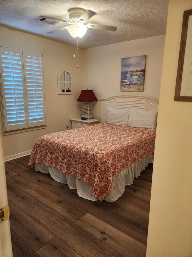 bedroom featuring dark wood-type flooring, ceiling fan, and a textured ceiling