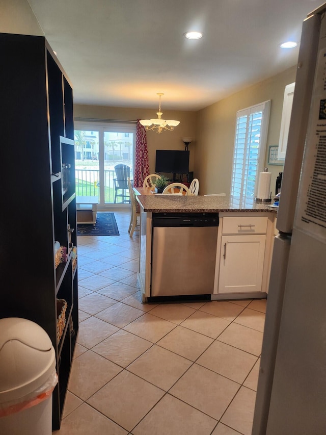 kitchen with appliances with stainless steel finishes, white cabinetry, light tile flooring, and a chandelier