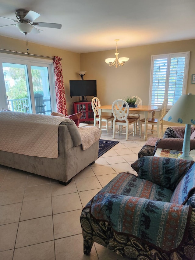 living room with a wealth of natural light, light tile floors, and ceiling fan with notable chandelier